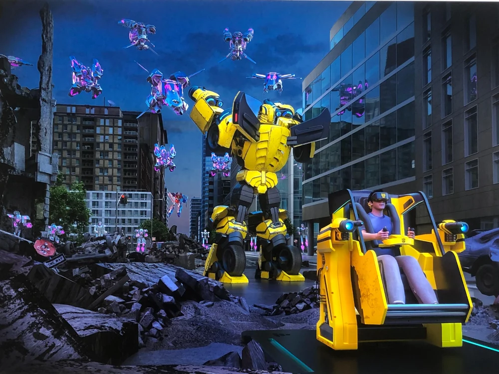 Transformers VR experience: a rider in a yellow motion seat facing a giant Bumblebee